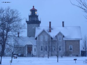 Backside of the lighthouse. Light is on, and it is snowing.
