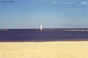 A distance shot of the lighthouse and a boat.