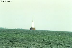Distance shot of lighthouse out in the water. A little blurry.