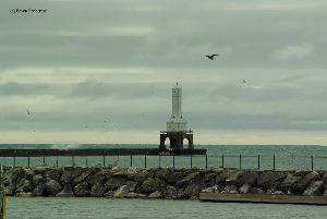 Waves crash over breakwall.