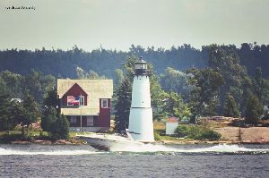 A boat races by the Rock Island Lighthouse.